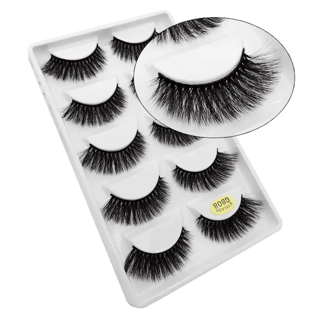 Luxurious 3D mink eyelashes in a beauty product display. Thick, voluminous lashes in a set of five pairs, perfect for enhancing the eyes with dramatic, glamorous appeal.